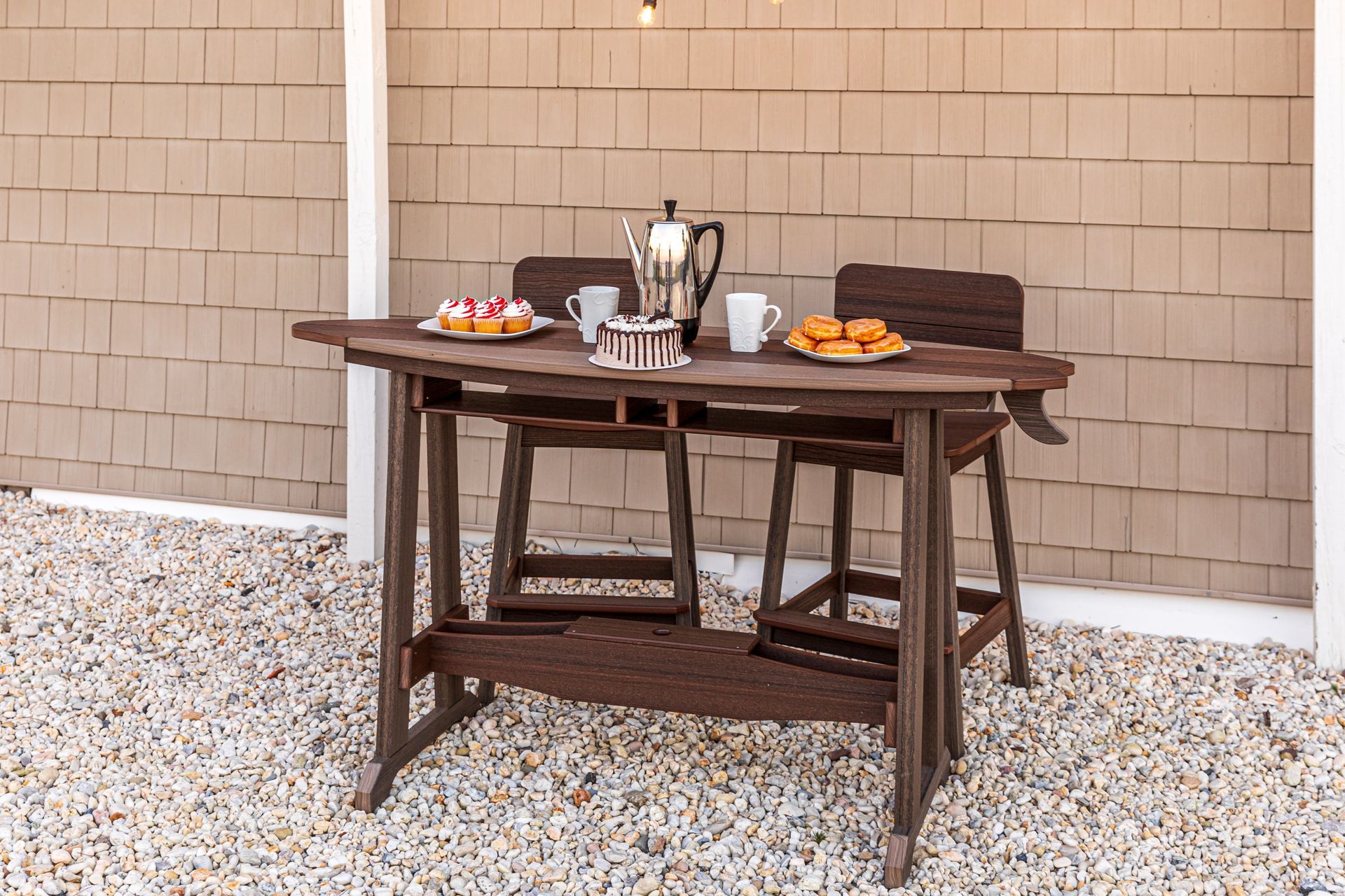 A wooden table with two chairs and plates of food on it.