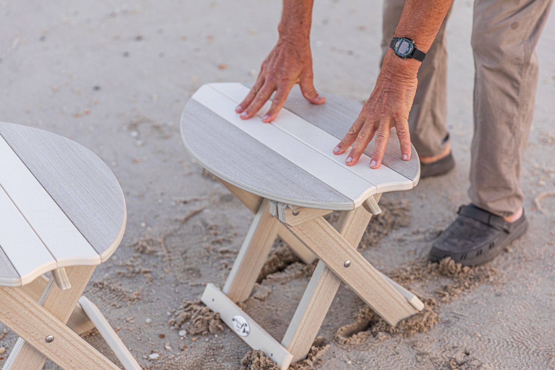 Two chairs and a table on a beach at sunset.
