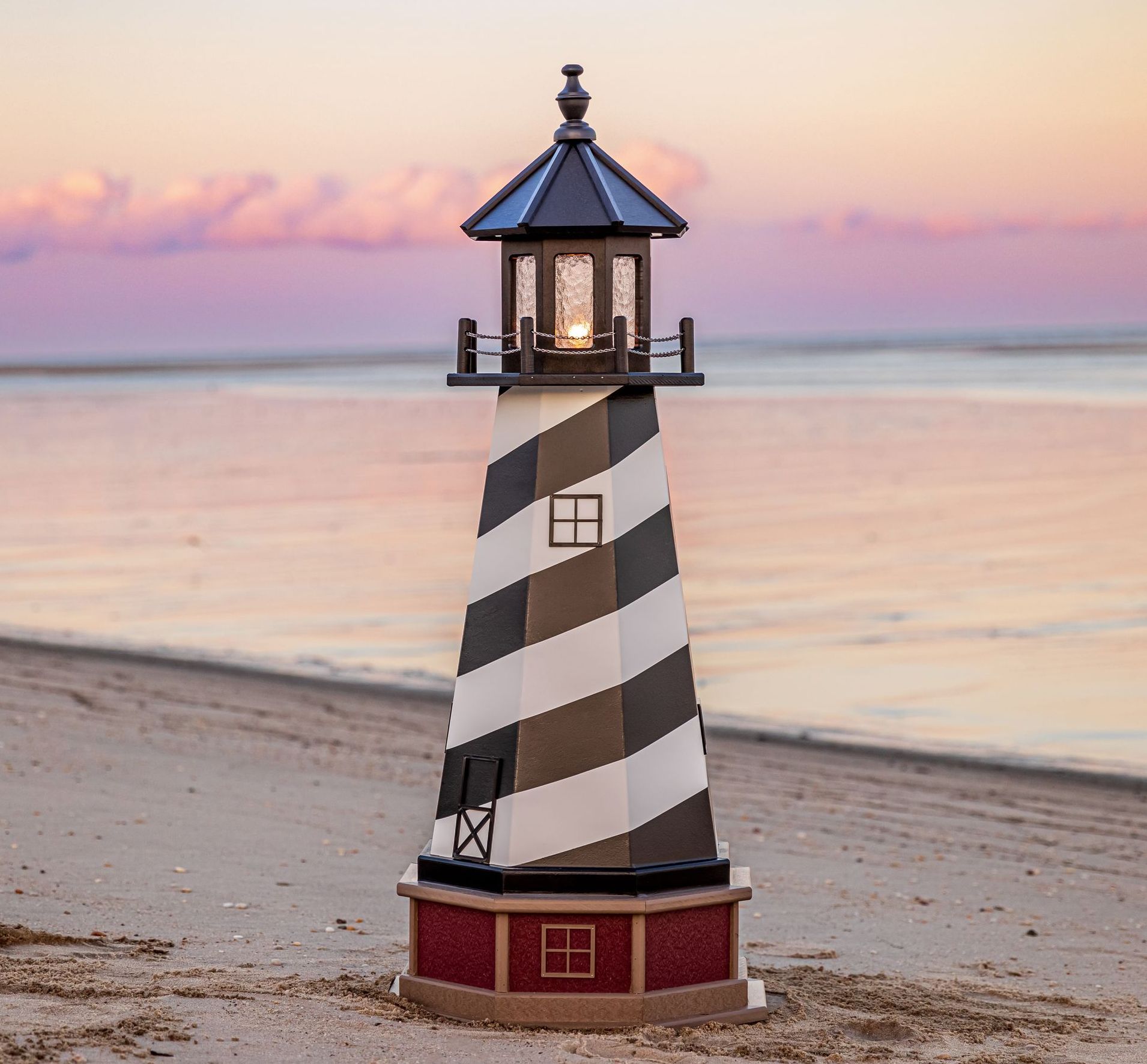 a black and white striped lighthouse on a beach