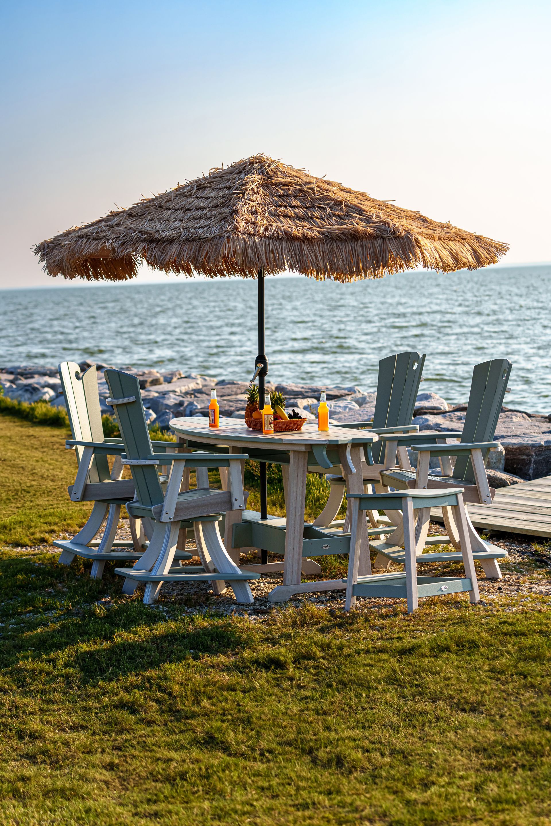 Two white chairs and a table on the beach with an umbrella.