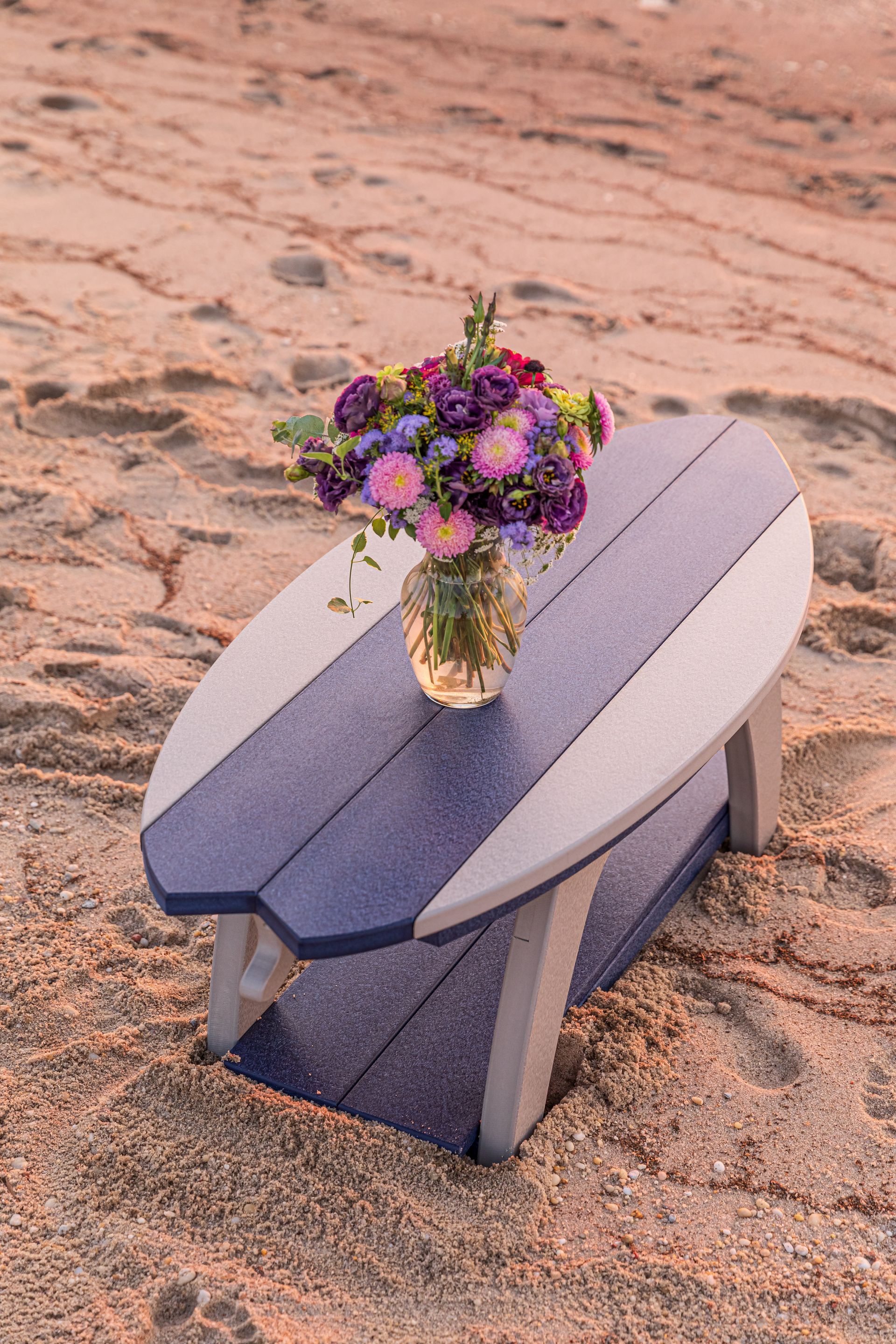 A surfboard table with a vase of flowers on it