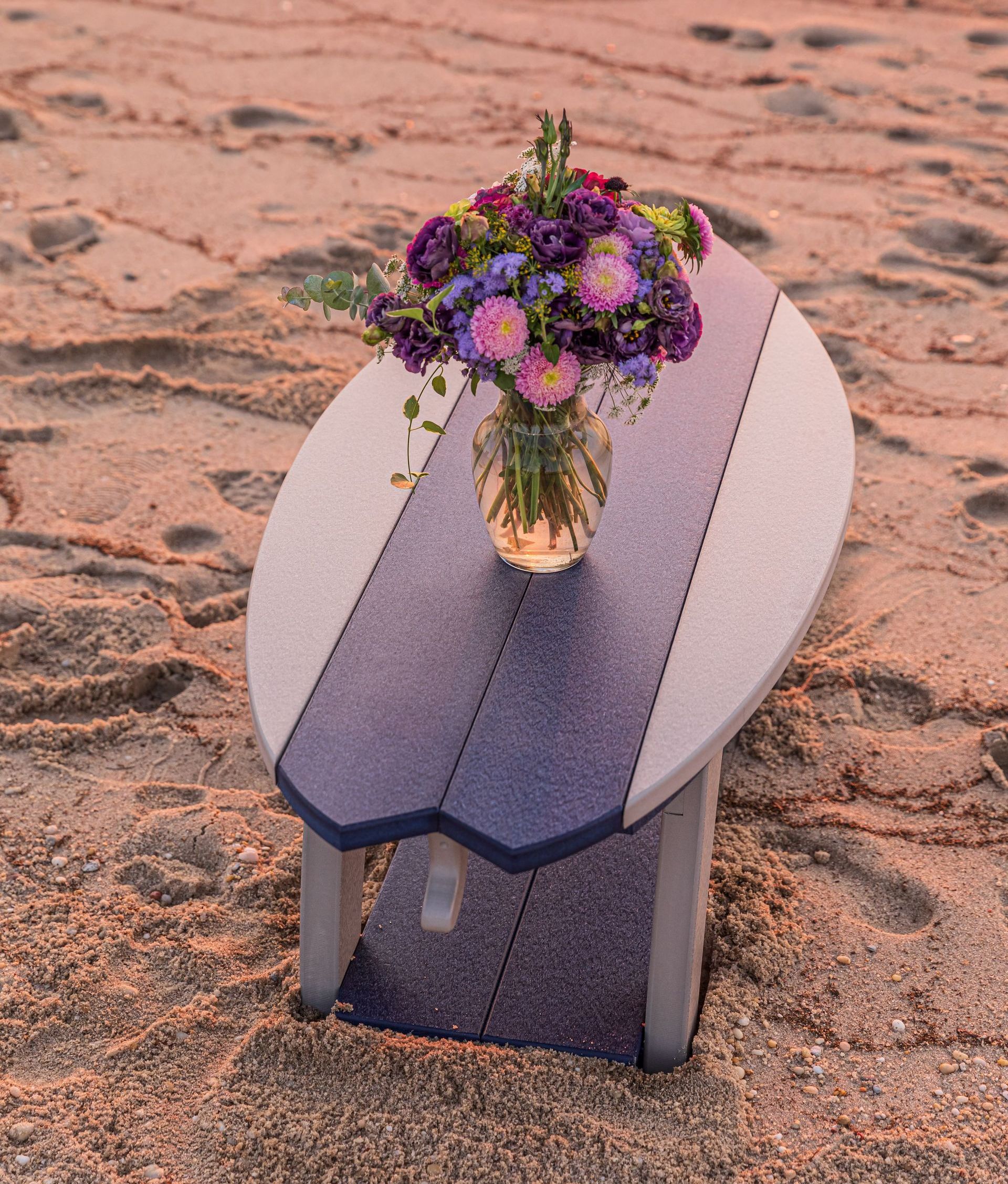 A surfboard table with a vase of flowers on it