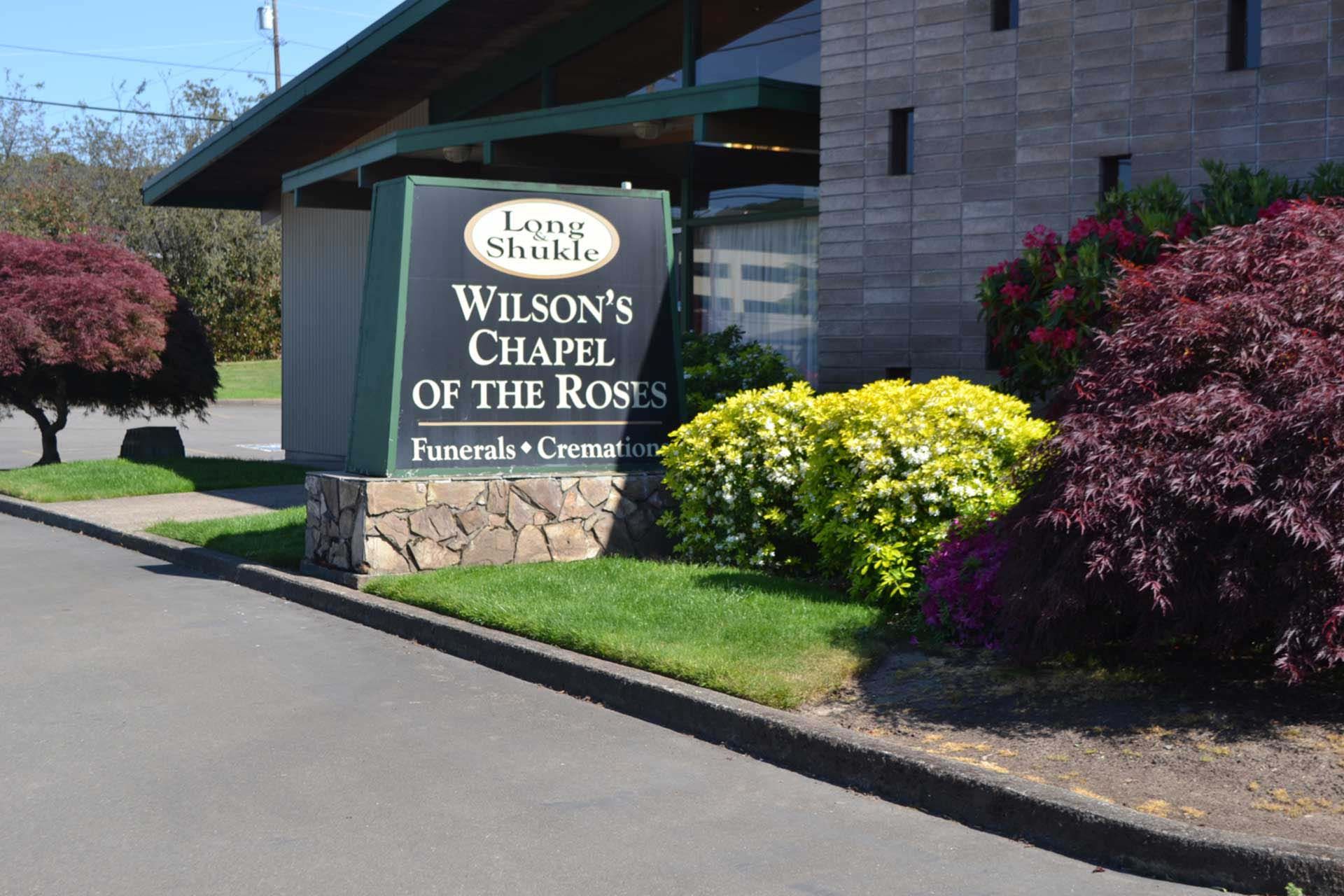 A sign for wilson 's chapel of the roses is in front of a building