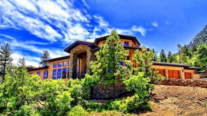 A large house is sitting on top of a hill surrounded by trees.