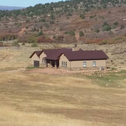 A house in the middle of a field with mountains in the background
