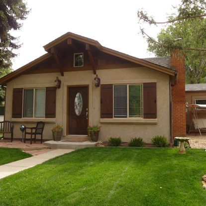A small house with brown shutters on the windows