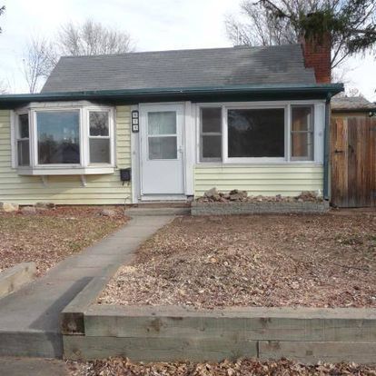 A small yellow house with a white door and windows