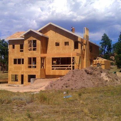 A large wooden house is being built in a field