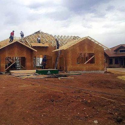 A group of people are working on the roof of a house under construction.