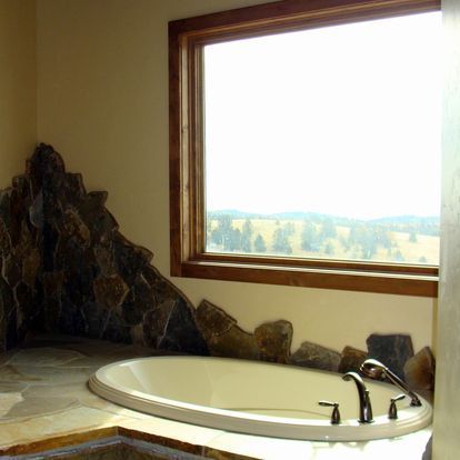 A bathtub in a bathroom next to a window