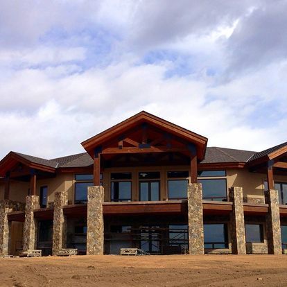 A large house with a lot of windows is sitting on top of a dirt hill.