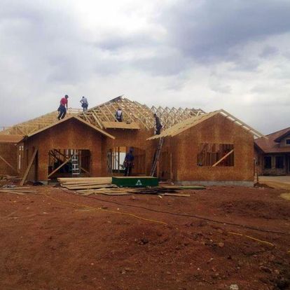 A group of people are working on the roof of a house under construction.