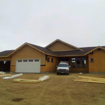 A car is parked in front of a house under construction.