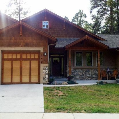 A house with a wooden garage door and a lawn in front of it