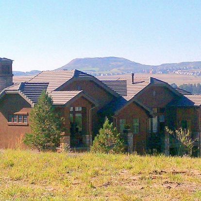 A large house sits in the middle of a grassy field