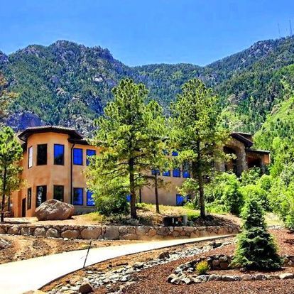 A house in the middle of a forest with mountains in the background