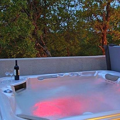 A hot tub with a bottle of wine and two glasses on a table.