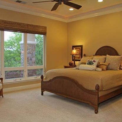 A bedroom with a large bed and a ceiling fan