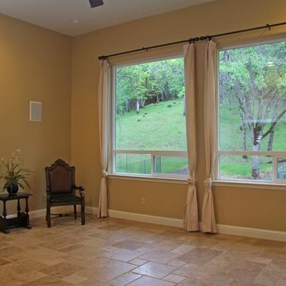 A living room with two large windows and a chair.