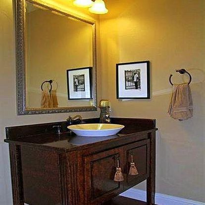 A bathroom with a sink , mirror , and towels hanging on the wall.