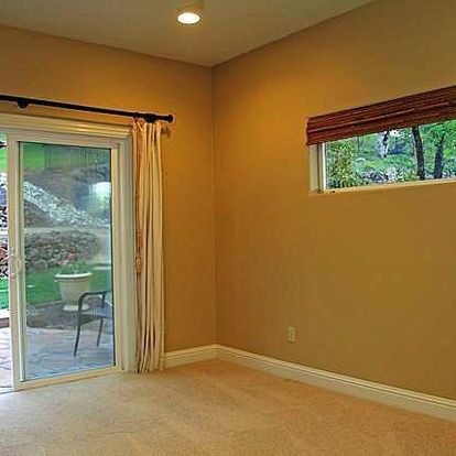 An empty room with a sliding glass door and two windows.