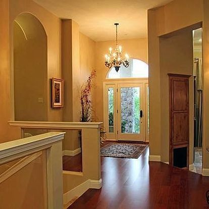 A hallway with hardwood floors and a chandelier hanging from the ceiling.