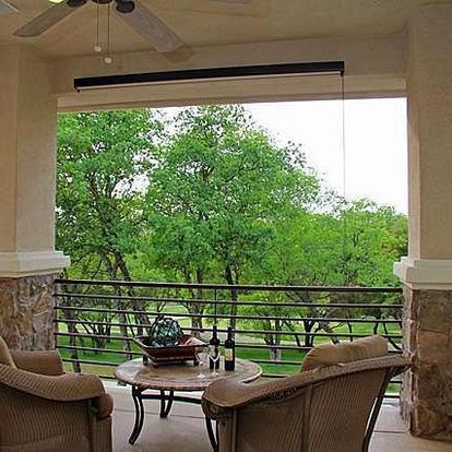 A balcony with two chairs and a table with a bottle of wine on it