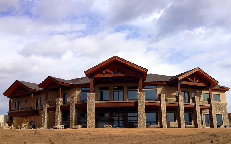 A large house is sitting in the middle of a dirt field