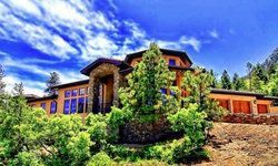 A large house is sitting on top of a hill surrounded by trees.