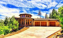 A large house with a lot of garage doors is sitting on top of a hill surrounded by trees.