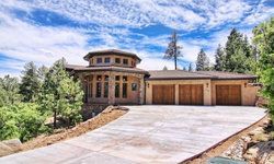 A large house with a driveway leading to it is surrounded by trees.