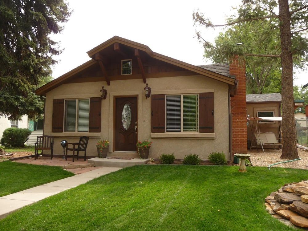 A small house with brown shutters on the windows