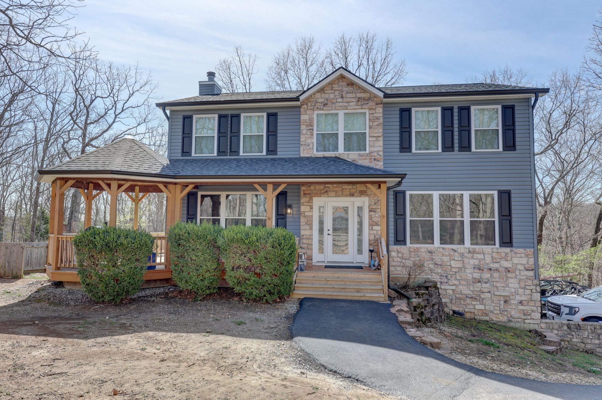 Two-story house with blue siding, stone accents, porch, gazebo, and walkway leading to the front door.