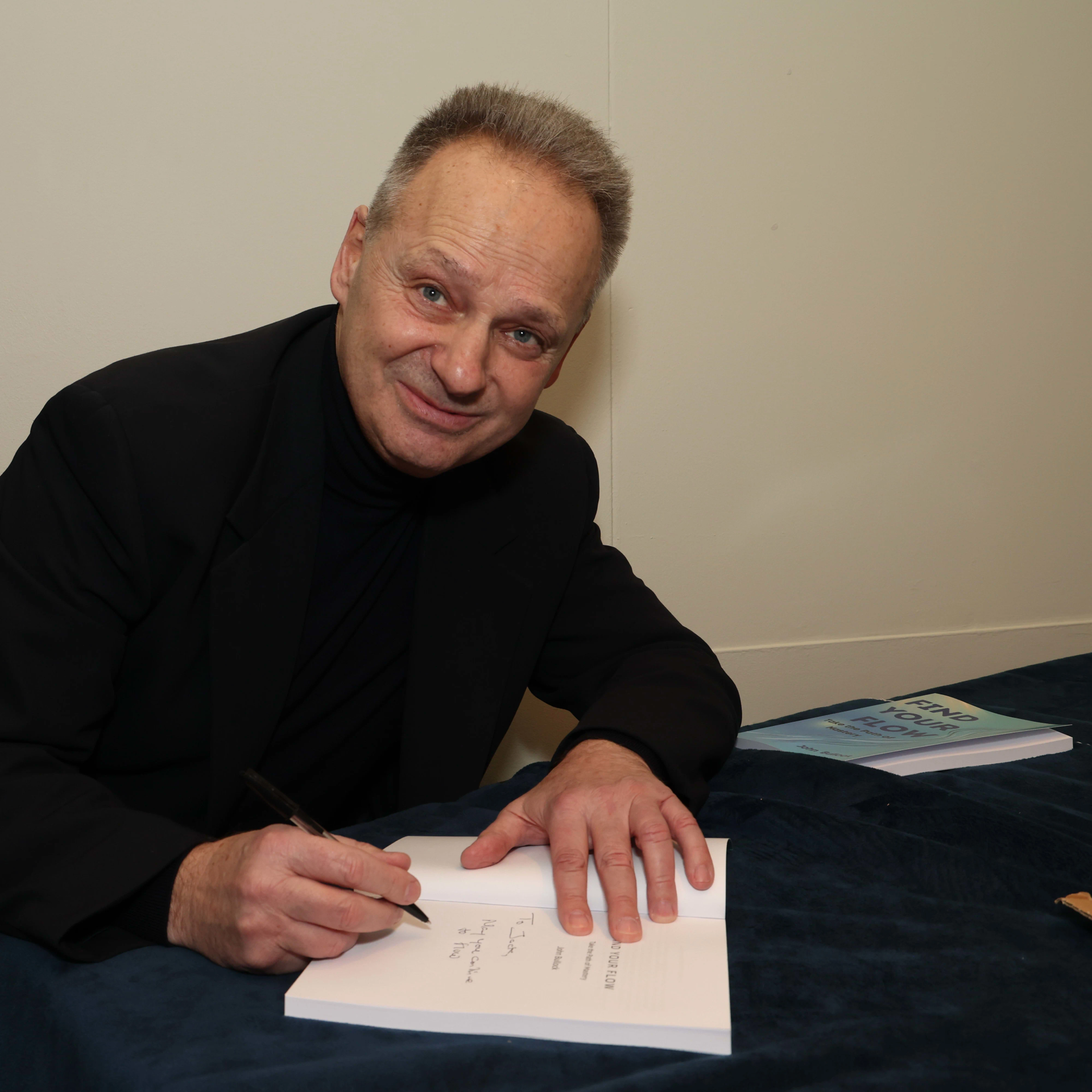 A man is sitting at a table writing in a notebook