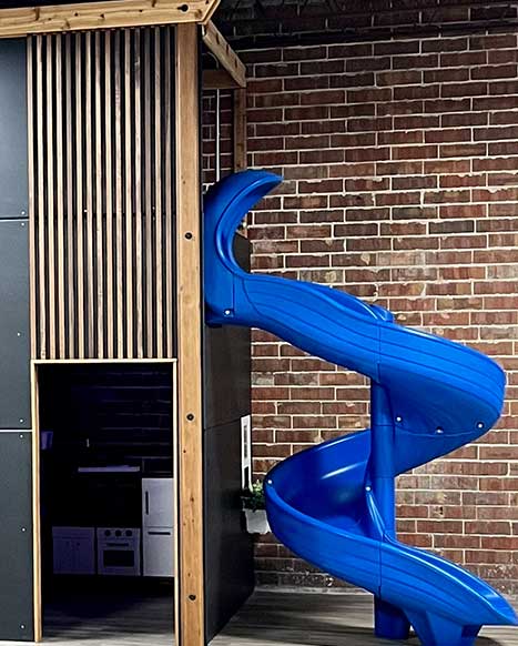 a blue slide is attached to a brick wall in a room .