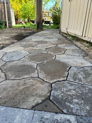 A stone walkway is being built next to a wooden fence.