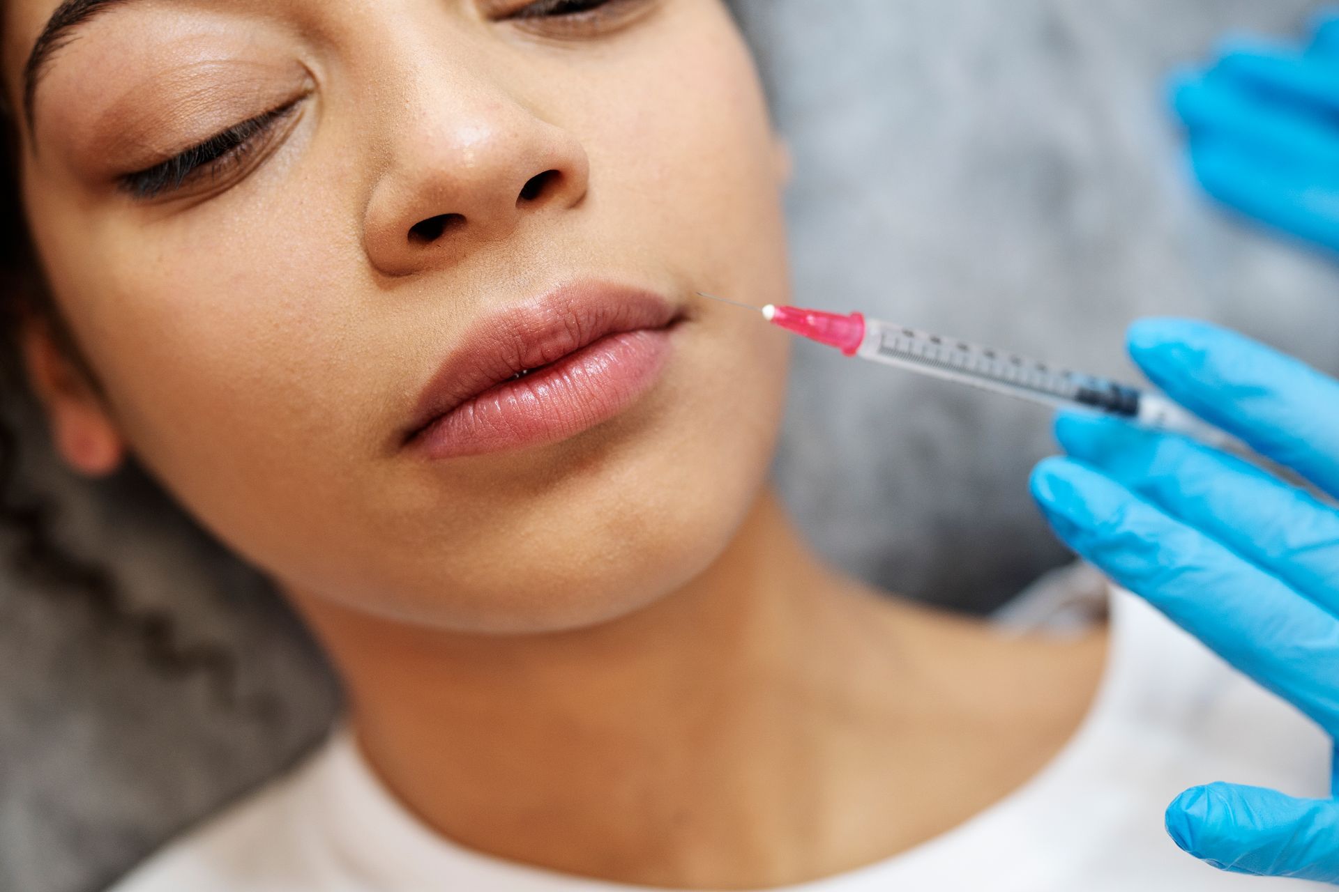 A woman is getting a botox injection in her lips.
