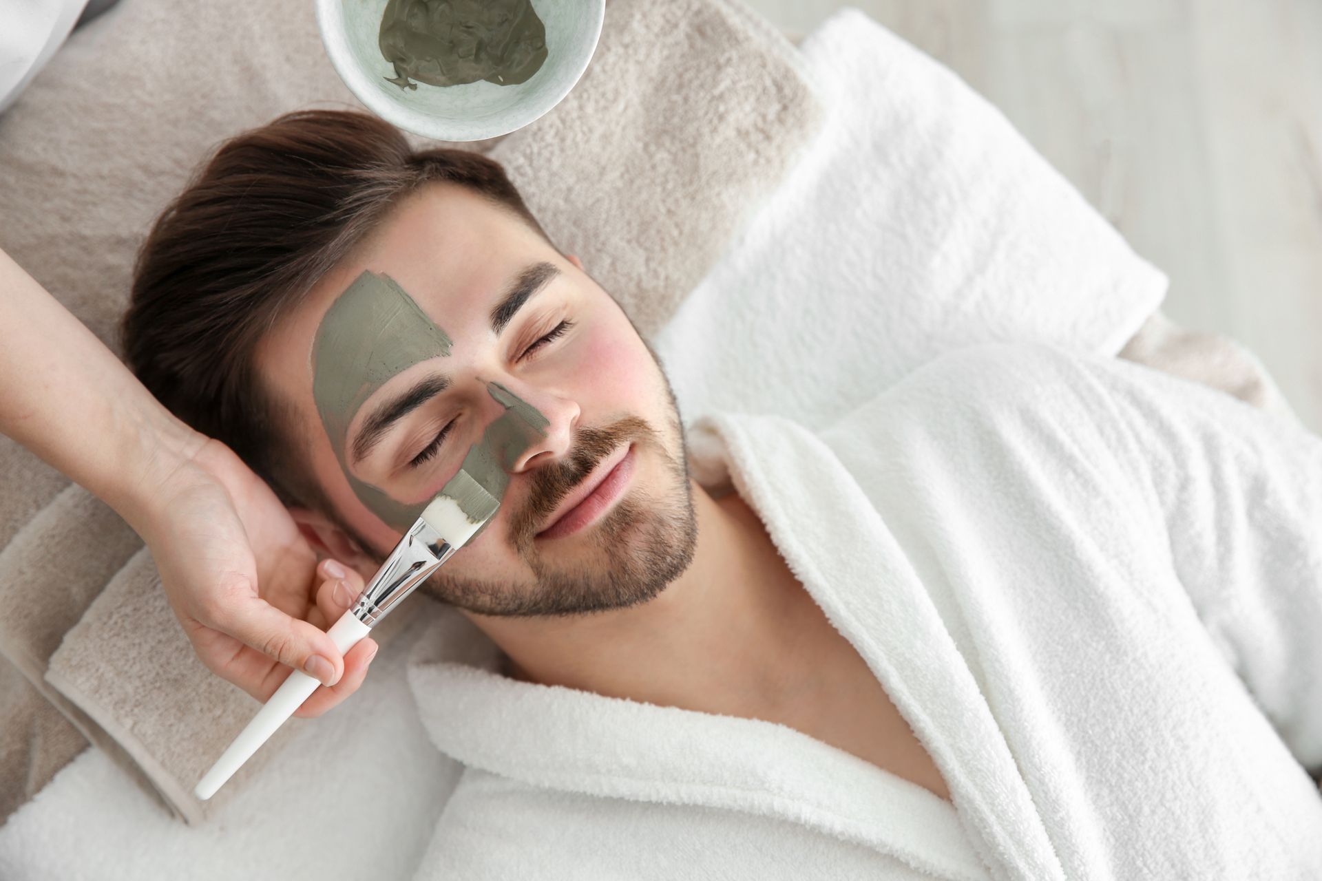 A man is getting a face mask at a spa.