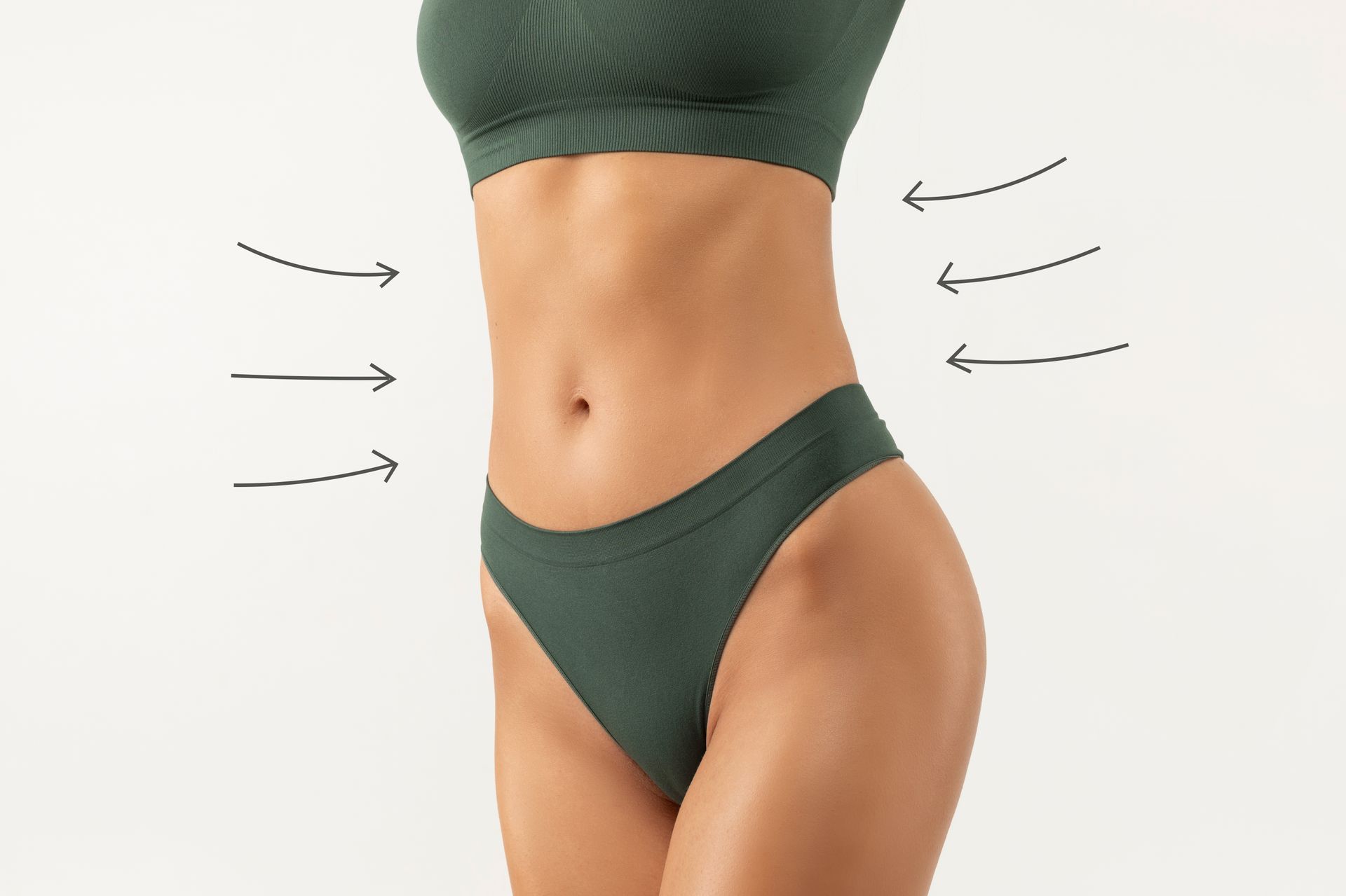 A woman in green underwear is showing her stomach with arrows pointing to it.