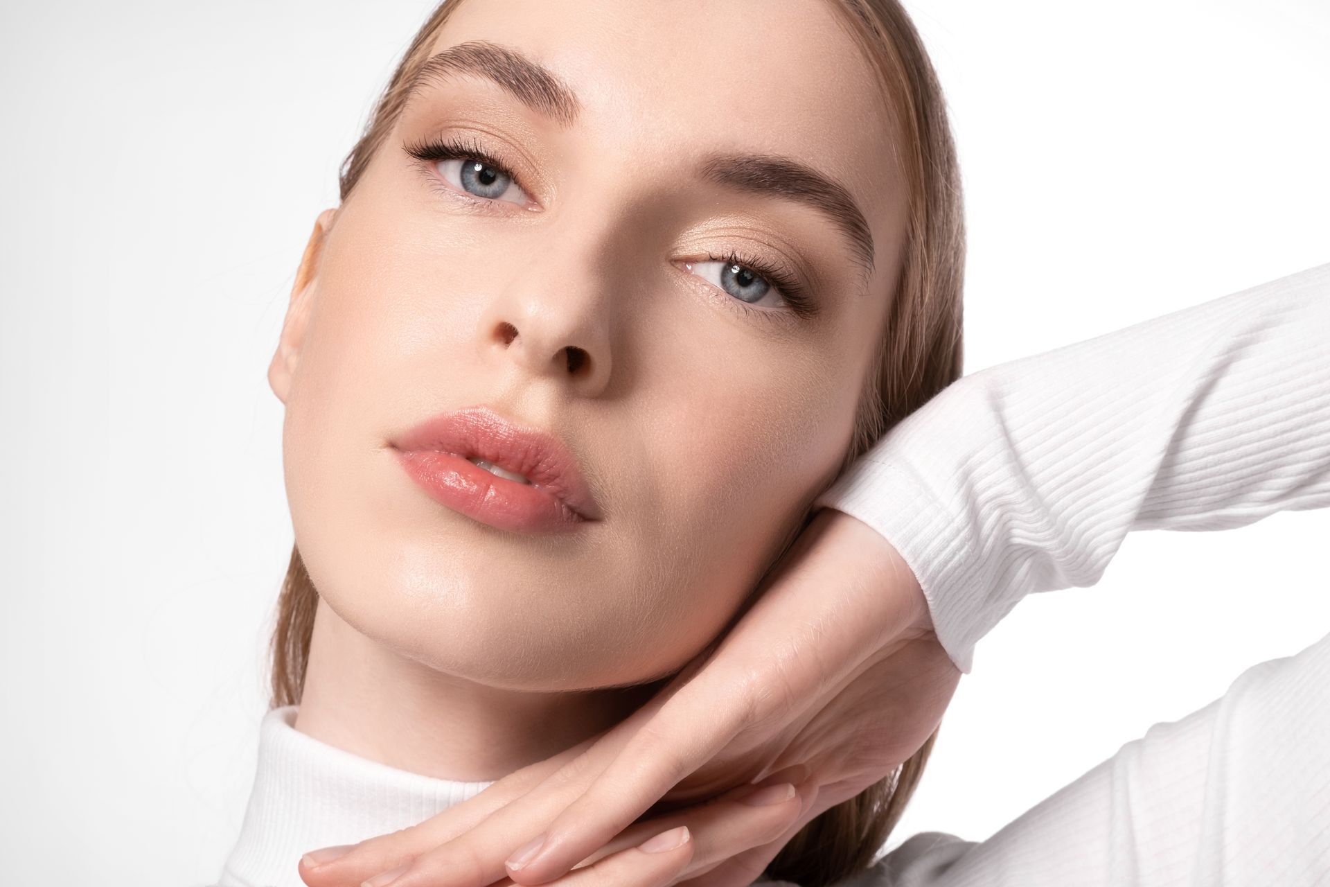 A close up of a woman 's face with her hand on her chin.