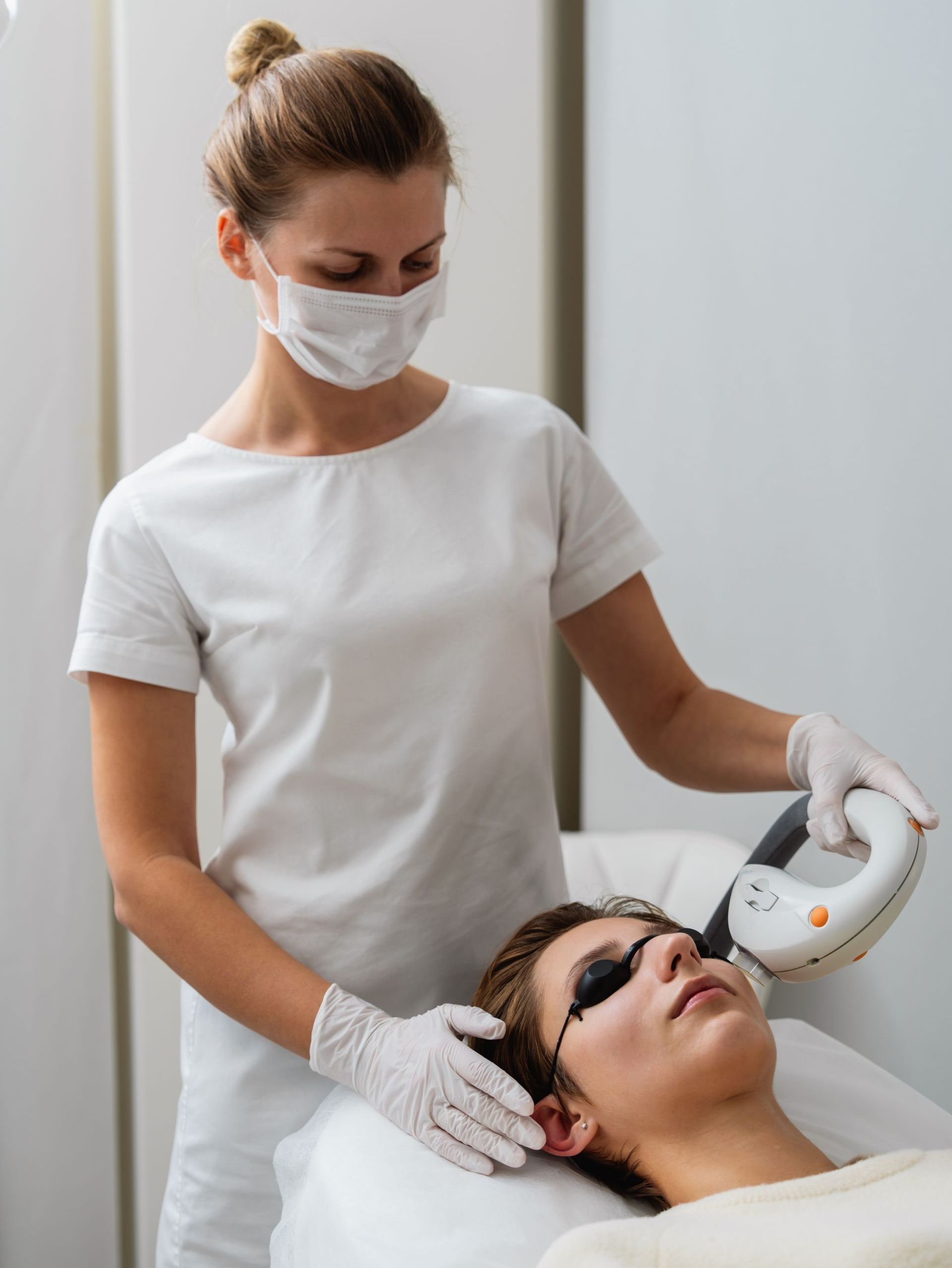 A woman is giving a man a laser treatment on his face.