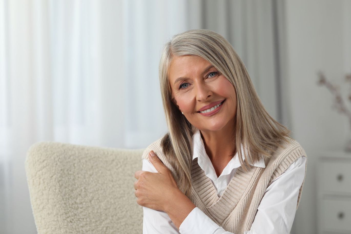 An older woman is sitting in a chair and smiling at the camera.
