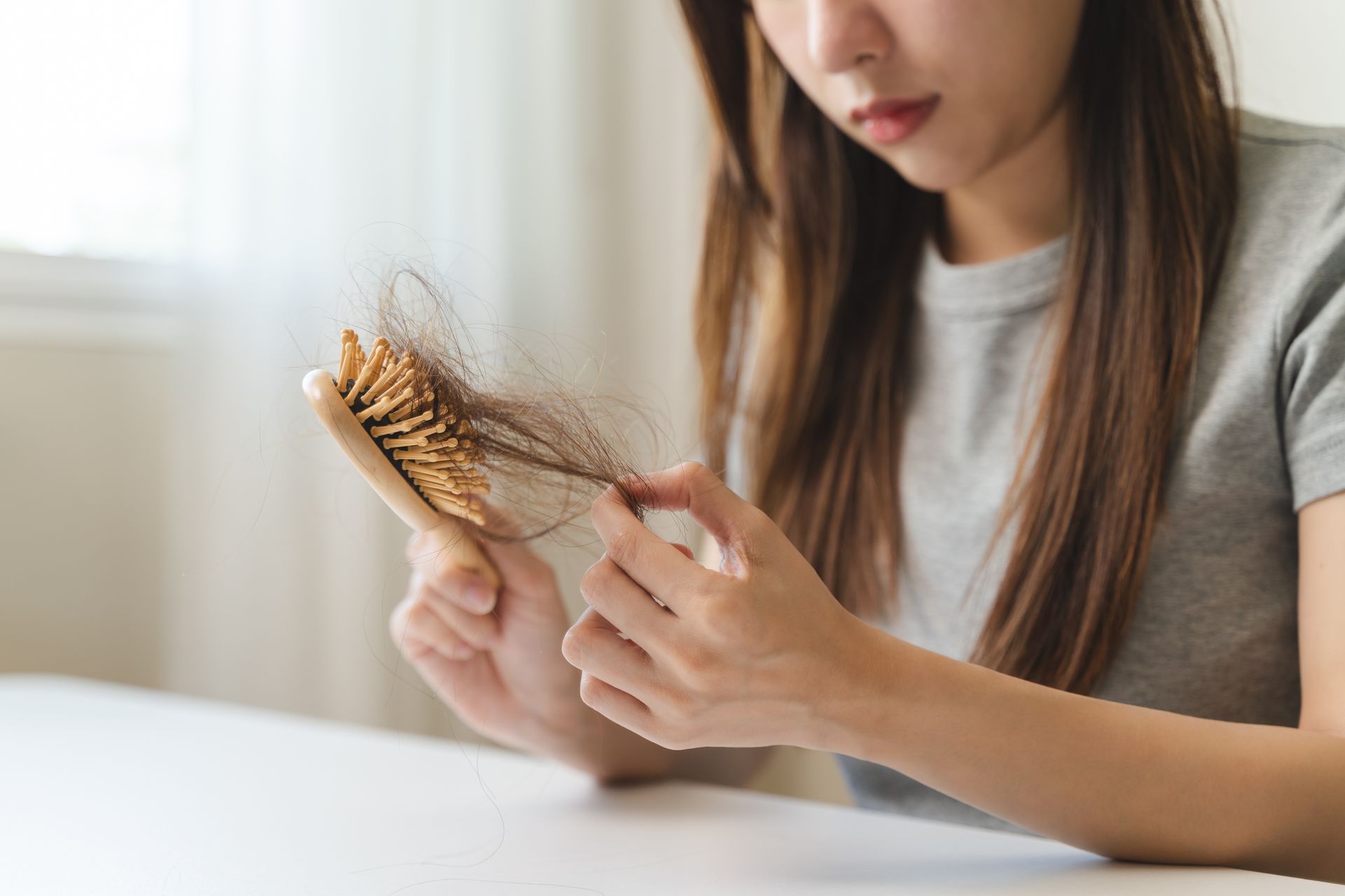 A woman is holding a brush with her hair on it.