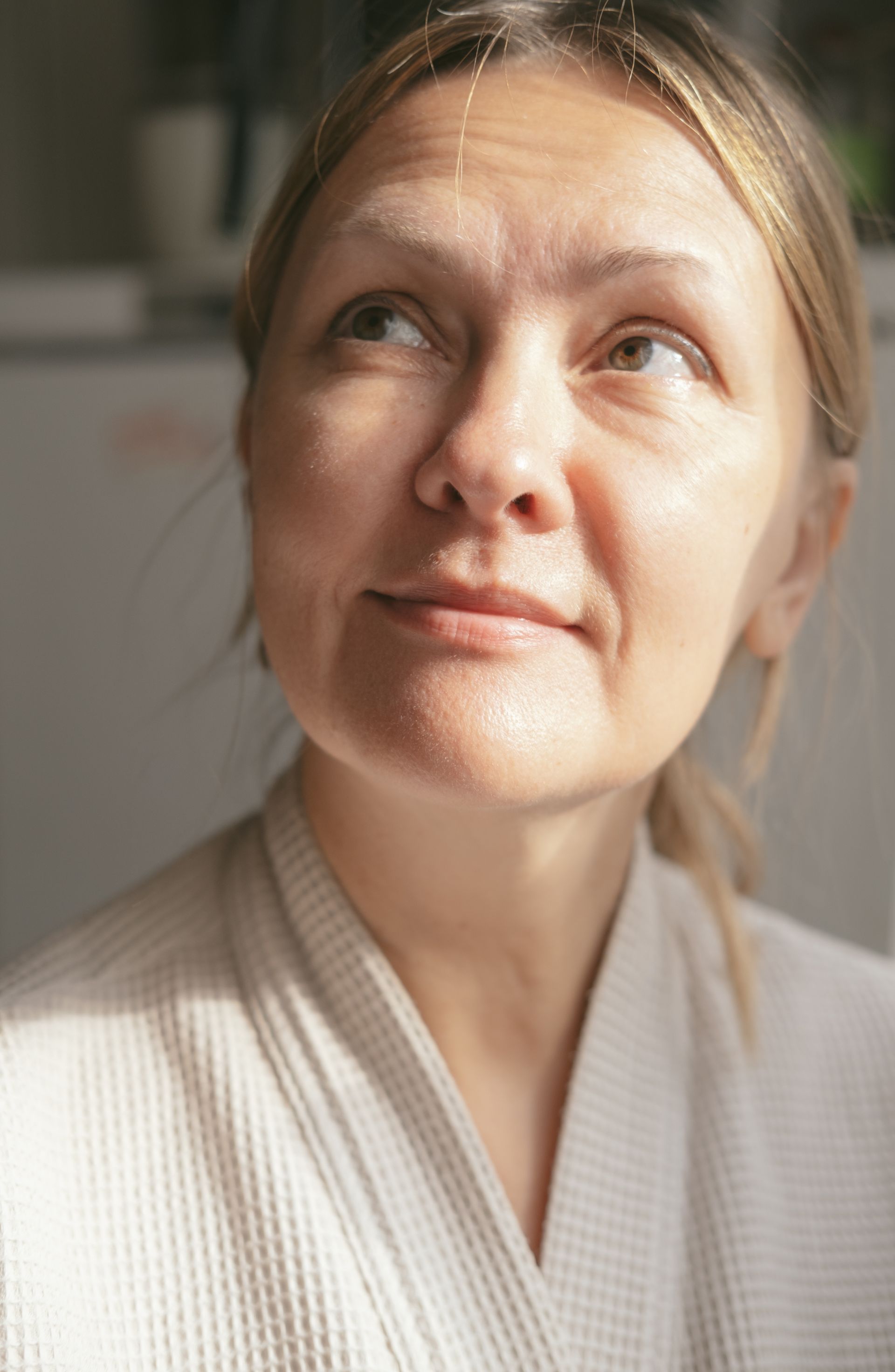 A woman in a white robe is looking up at the sky.