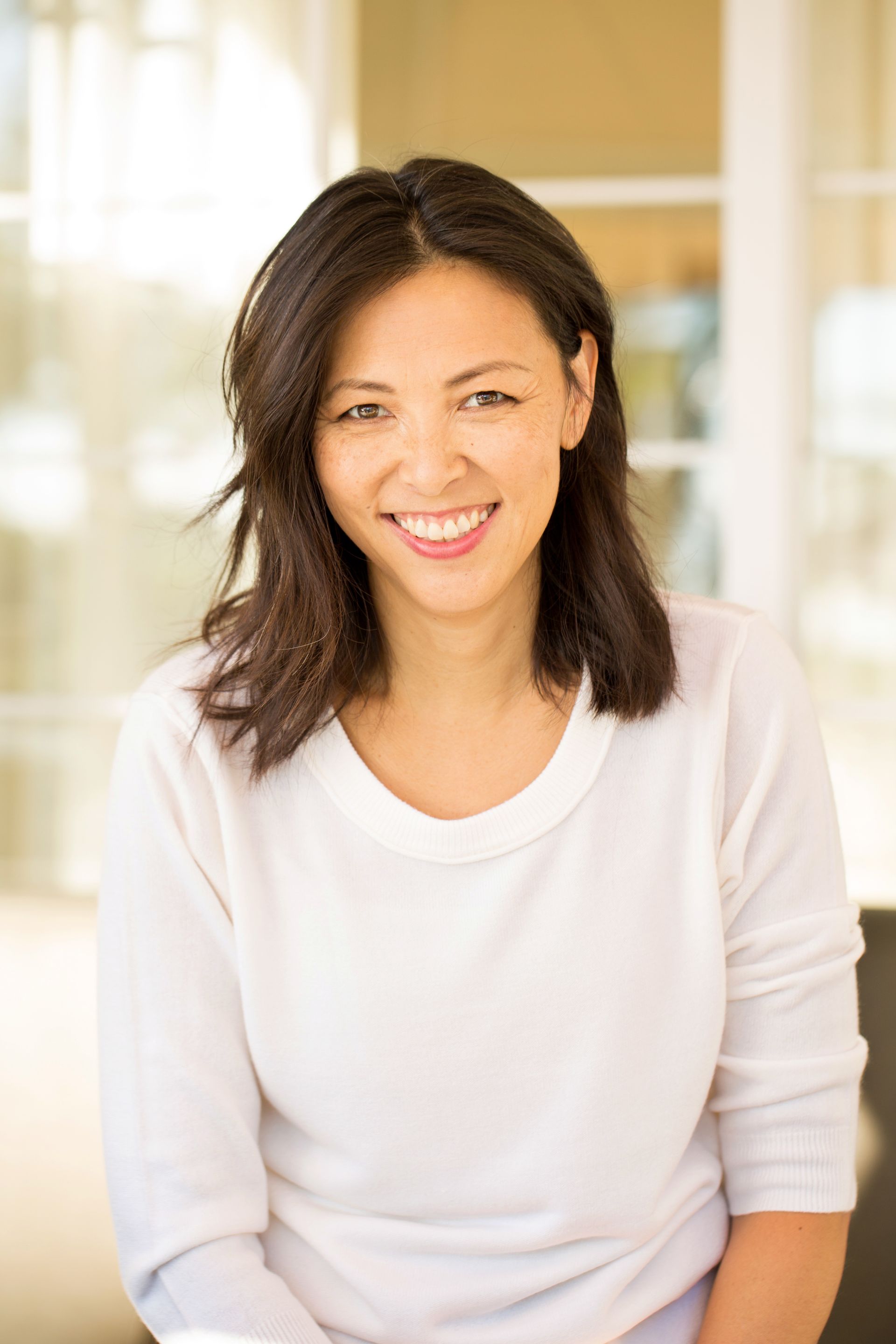 A woman in a white sweater is smiling for the camera.