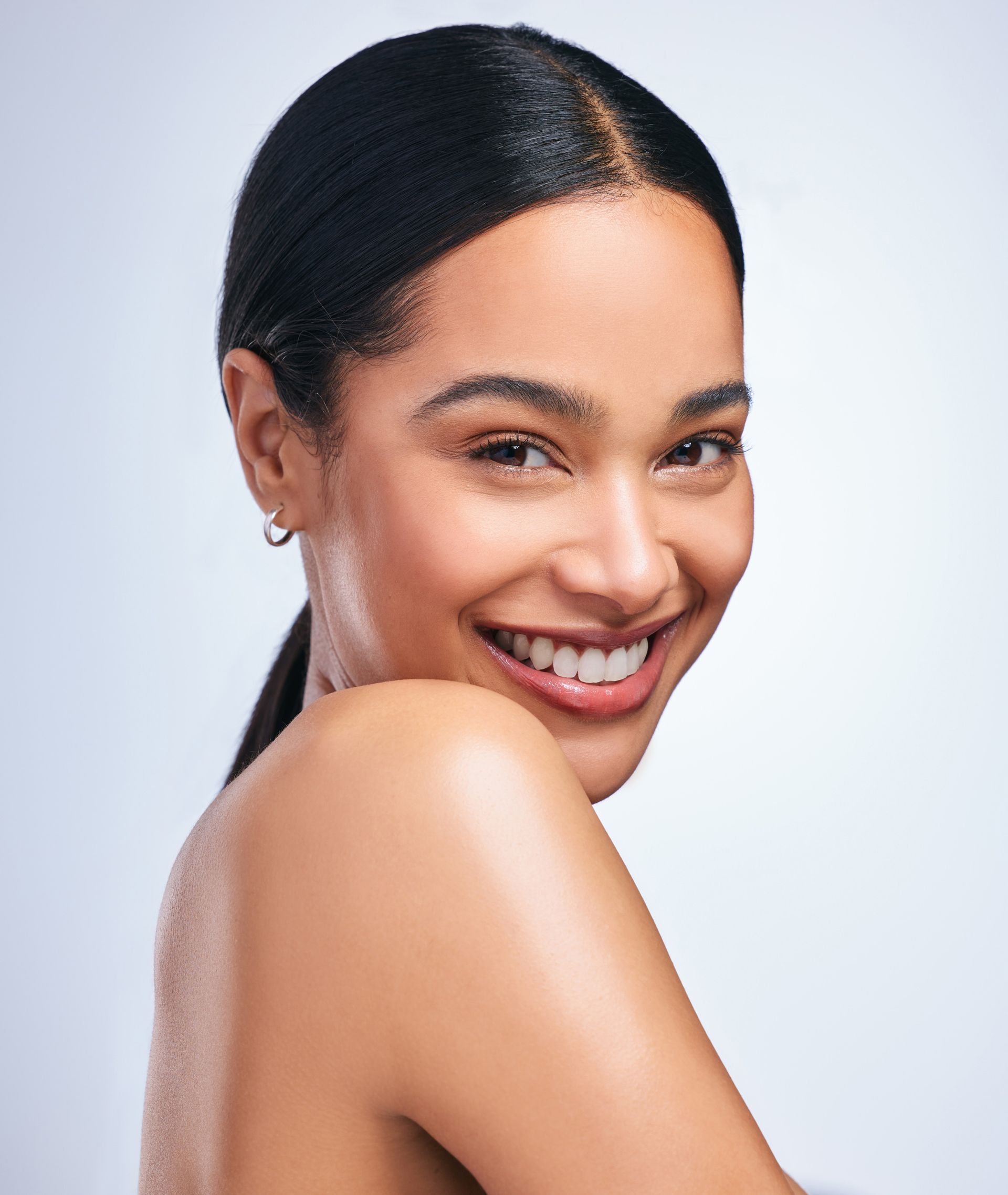 A woman is smiling and looking over her shoulder at the camera.