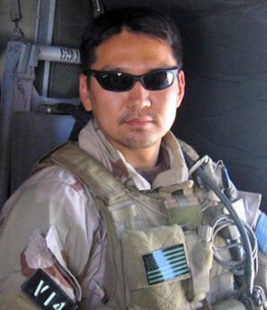 A man wearing sunglasses and a vest that says via