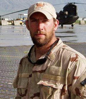 A man in a military uniform is standing in front of a helicopter