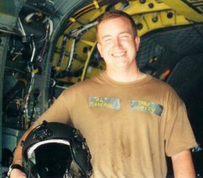 A man holding a helmet and wearing a t-shirt that says united states navy