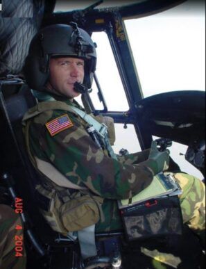 A man in a military uniform is sitting in the cockpit of a helicopter on august 4 2004